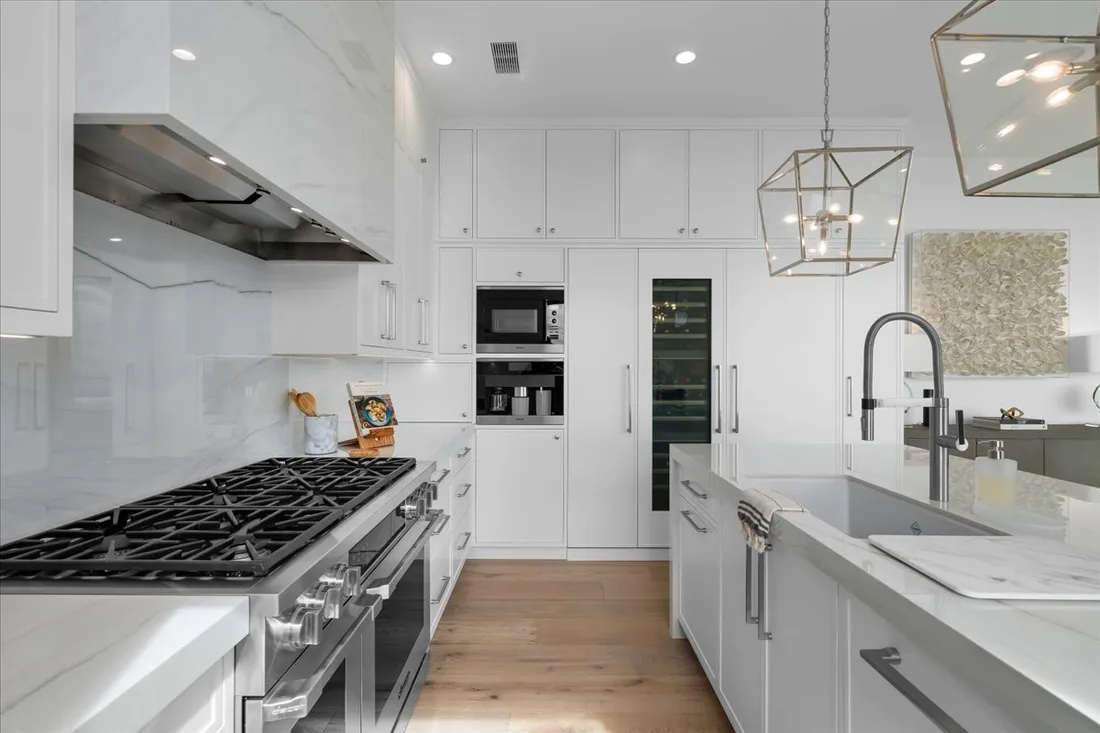 Professional stainless range, custom hood and full-height slab backsplash anchoring an estate-scale Palos Verdes kitchen.