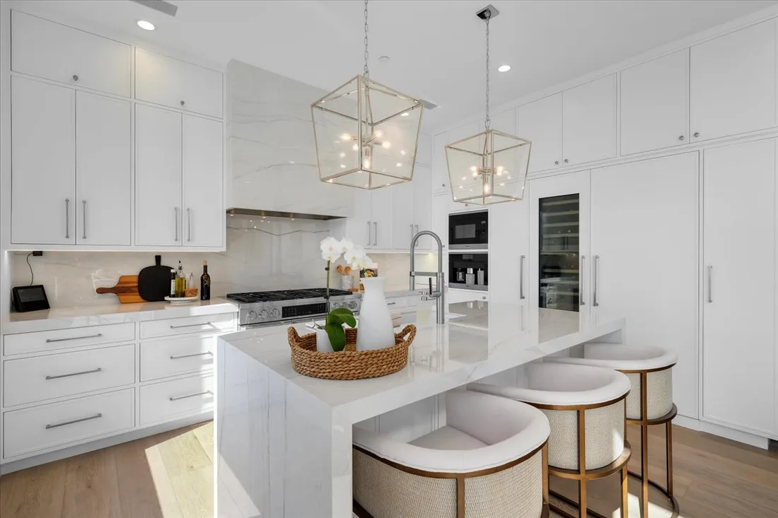 Waterfall-edge quartzite island, lantern pendants and panel-ready refrigeration in an estate-scale Palos Verdes kitchen.
