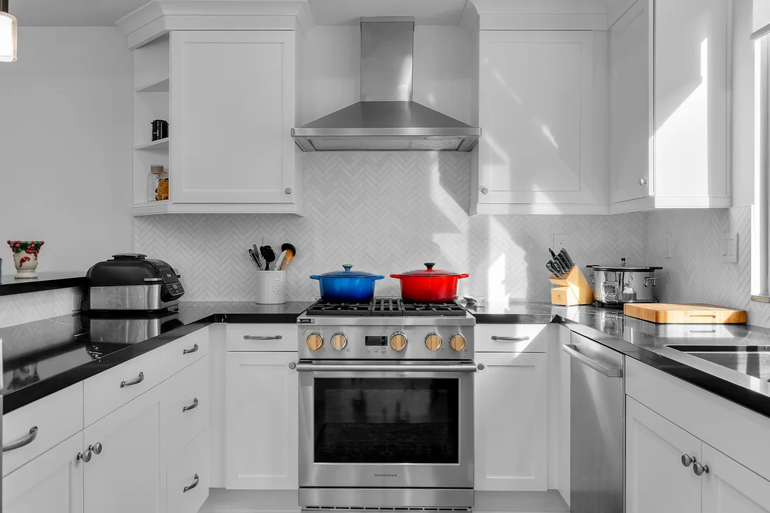 Wolf gas range set against a white marble herringbone backsplash in a bright white Torrance kitchen remodel.