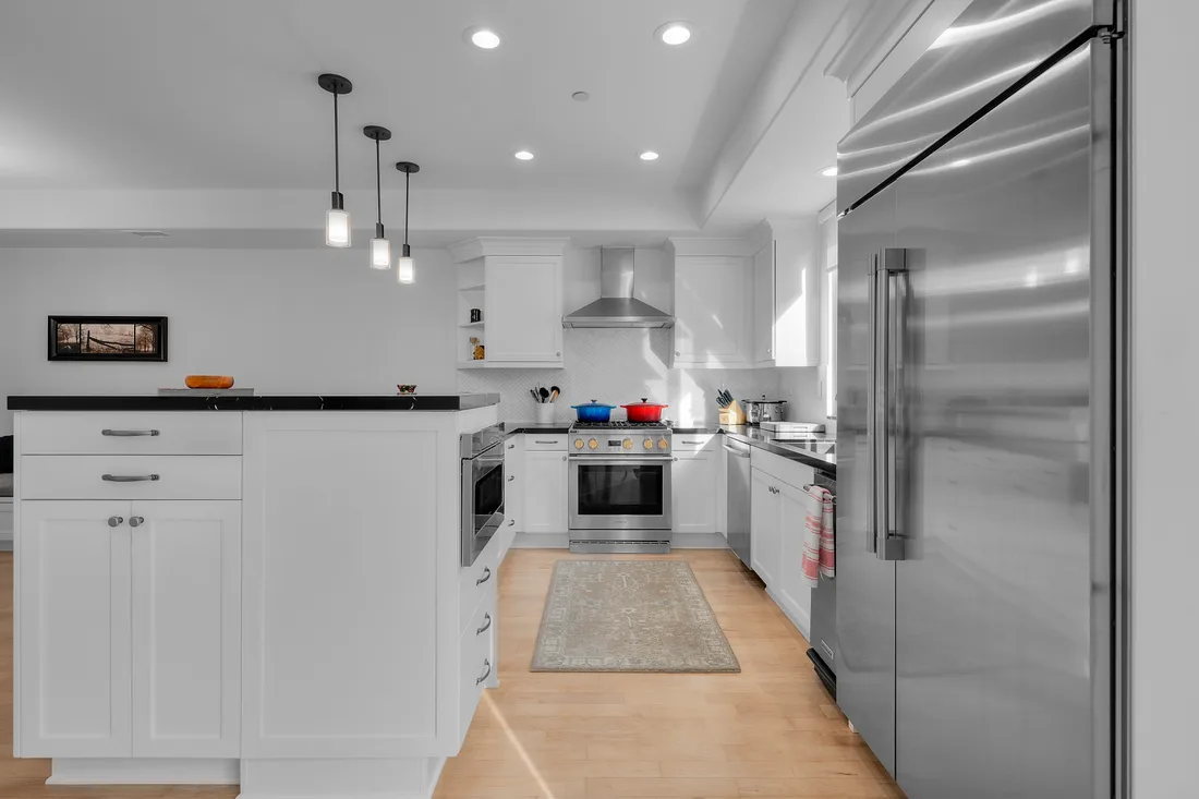 Sub-Zero refrigeration and a Wolf range framed by white shaker cabinetry and industrial pendants in a Torrance kitchen remodel.