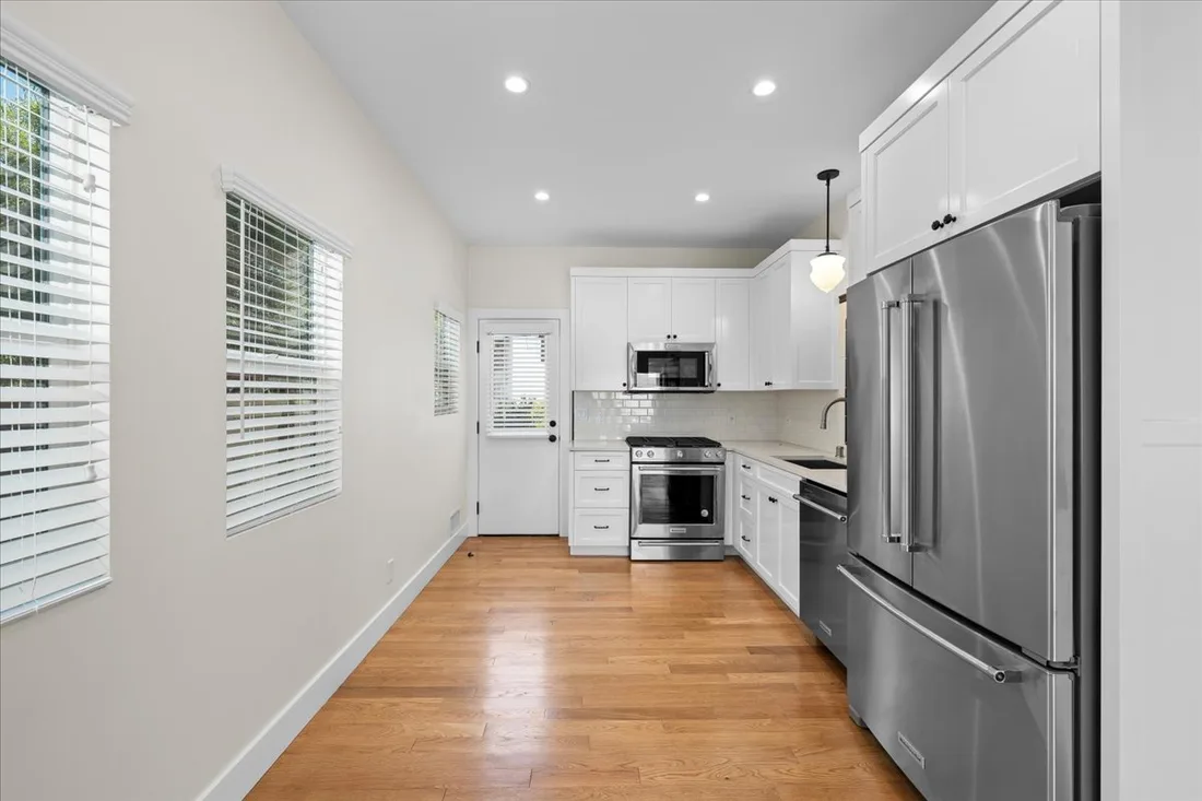 White shaker galley cabinetry lining both walls with stainless appliances and light hardwood floors in a compact Torrance kitchen.